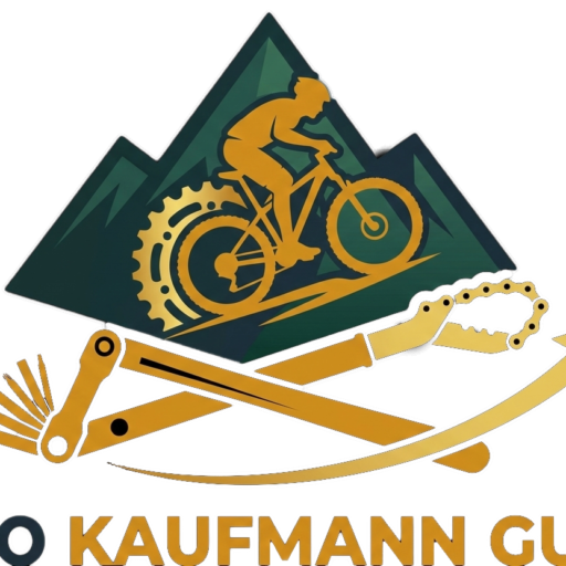 Logo mit stilisiertem goldenen Mountainbiker vor Bergsilhouette; darunter gekreuzte Fahrradwerkzeuge und der Schriftzug „VELO KAUFMANN GUOLO“.